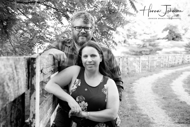 Black and white engagement photo with horse fence in barn lot in cynthiana Kentucky