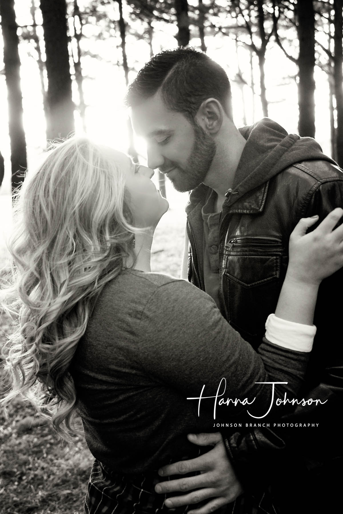 Black and white engagement photo in Lexington, KY with pines trees and back lighting. 